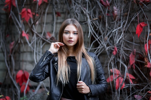 Girl in a leather jacket and red maple leaf behind her Stock Photo