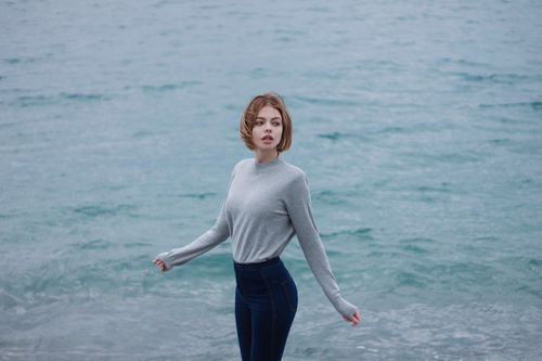 Girl in grey sweater stands by the river Stock Photo