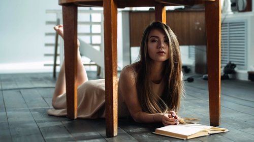 Girl reading a book under the table Stock Photo