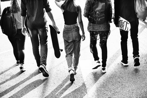 Grayscale photography of five young people walking on the road Stock Photo