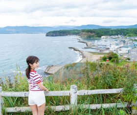 Japanese girl standing on the hillside looking at the sea Stock Photo