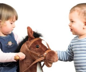 Little girl and little boy riding wooden horse Stock Photo