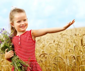 Little girl holding bouquet in wheat field Stock Photo