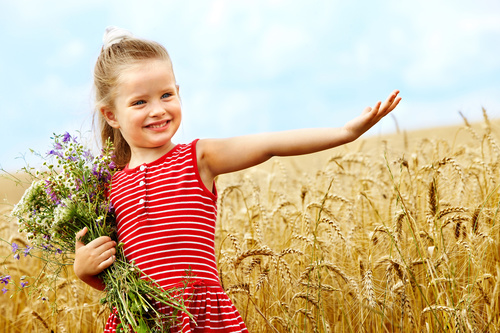Little girl holding bouquet in wheat field Stock Photo