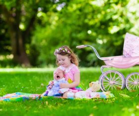 Little girl playing with newborn baby brother in summer park Stock Photo 01