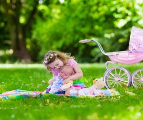 Little girl playing with newborn baby brother in summer park Stock Photo 02