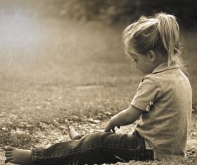 Little girl sitting on the ground playing Stock Photo