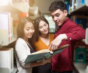 Male and female college students reading books in the library Stock Photo