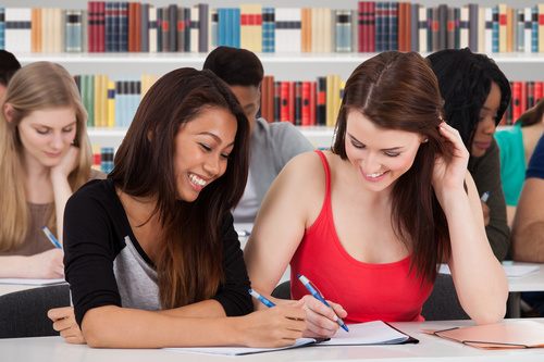 Smiling female college student writing homework Stock Photo