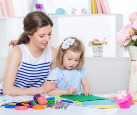 Stock Photo Young mother watching her daughter draw