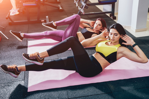 Two women doing abdominal exercises in the gym Stock Photo