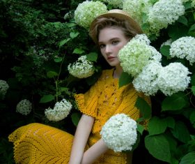 Wearing yellow dress women sitting in flowering shrubs Stock Photo