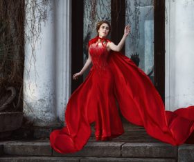 Woman in red dress and cloak outdoors Stock Photo