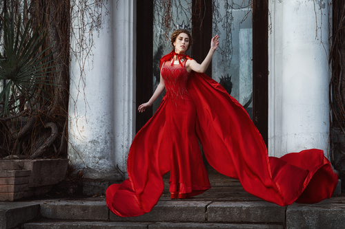 Woman in red dress and cloak outdoors Stock Photo