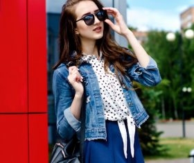 Woman on the street wearing sunglasses and denim jacket and short skirt Stock Photo