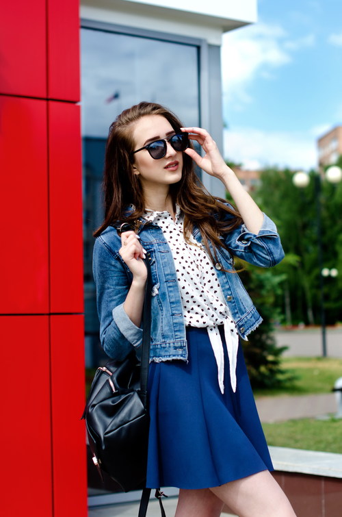Woman on the street wearing sunglasses and denim jacket and short skirt Stock Photo