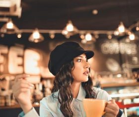 Woman sitting in cafe drinking coffee looking into the distance Stock Photo