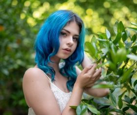 Woman with blue hair outdoors and green plants Stock Photo