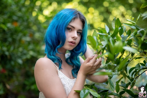 Woman with blue hair outdoors and green plants Stock Photo