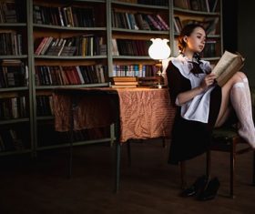 Women indoors reading under lamp light Stock Photo