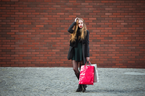 Young woman standing in front of red wall holding shopping bags Stock Photo 02