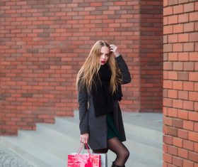 Young woman standing in front of red wall holding shopping bags Stock Photo 03