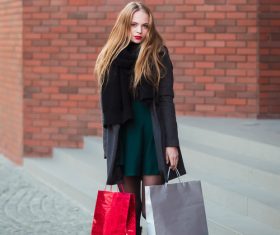 Young woman standing in front of red wall holding shopping bags Stock Photo 04