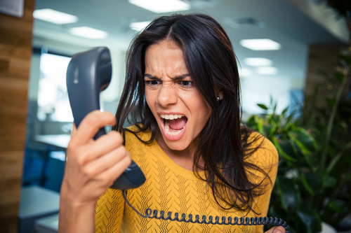 Angry woman holding telephone receiver Stock Photo