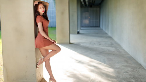 Asian woman in short skirt leaning on stone pillar Stock Photo