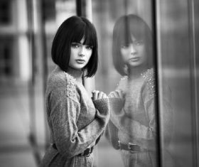Black and white photo of woman standing in front of glass window Stock Photo