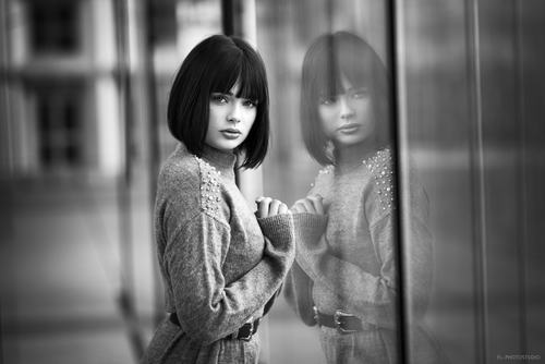 Black and white photo of woman standing in front of glass window Stock Photo