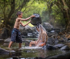 Children in the river holding bamboo baskets splashing water Stock Photo
