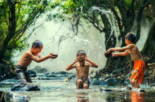 Children in the river splash each other Stock Photo