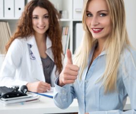 Female patient thumbs up praising female doctor Stock Photo