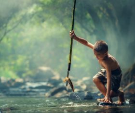 Little boy catching fish with harpoon in the river Stock Photo