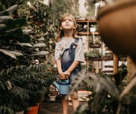Little girl holding watering can in botanical garden Stock Photo