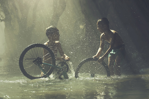 Two children cleaning bicycles in the river Stock Photo