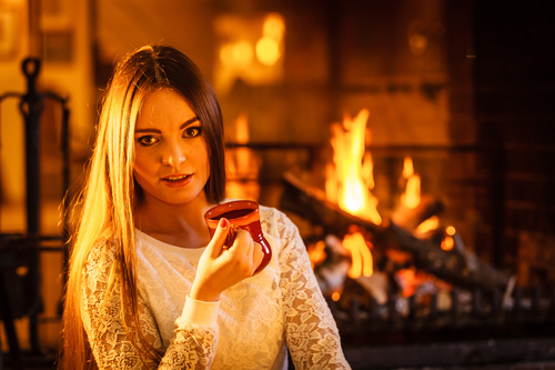 Woman drinking coffee by the fireplace Stock Photo 01
