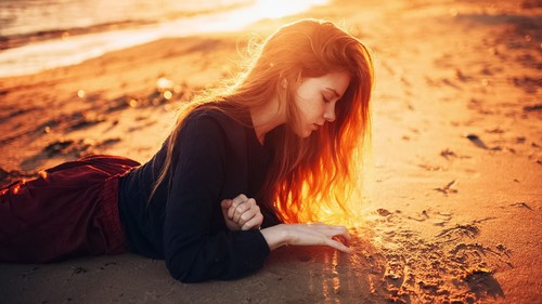 Woman kneeling on the beach writing on the beach Stock Photo