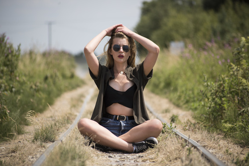 Woman sitting on the abandoned railway combing hair Stock Photo