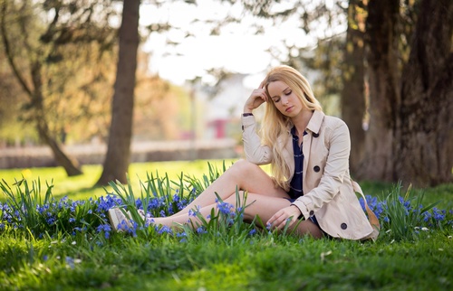 Woman sitting on the grass in the park with blue flowers Stock Photo
