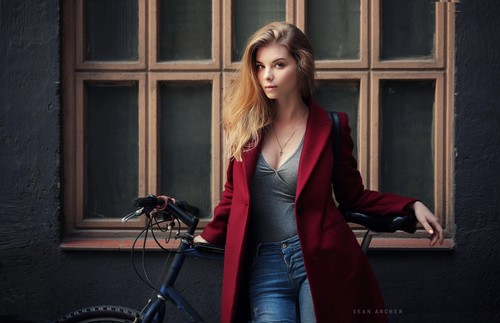 Woman wearing red coat standing at the window and bicycle Stock Photo