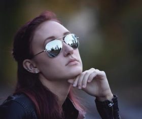 Woman with hand on chin wearing sunglasses and nose ring Stock Photo